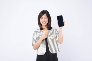 Güneydoğu Asyalı kadın internet uygulamasını gösteren cep telefonu ekranına mutlu bir şekilde işaret ederek, parlak stüdyo ortamında heyecan ve kullanım kolaylığı gösteriyor