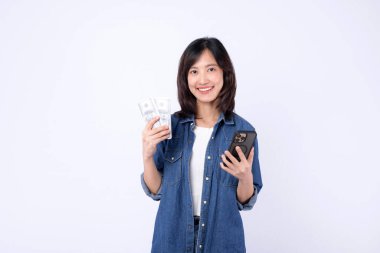 Cep telefonu ve nakit parayla gülümseyen Güneydoğu Asyalı kadın İnternet başvurusu başarısını gösteriyor