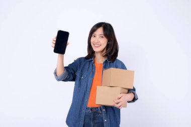 Güneydoğu Asyalı kadın elinde iki karton kutu tutarken ve internetten alışveriş yaparken akıllı telefon ekranı gösterirken mutlu bir şekilde gülümsüyor.