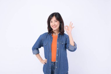 Güneydoğu Asyalı kadın gülümsüyor ve günlük kot ve turuncu tişörtle reklam tarzında iyi bir jest yapıyor.