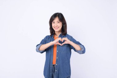 Güneydoğu Asyalı kadın sıcak bir şekilde gülümsüyor ve sevgi ve şefkat mesajı vermek için elleriyle kalbini şekillendiriyor.