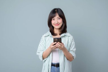 Güneydoğu Asyalı kadın, küçük işletme çevrimiçi mağazası için akıllı telefonu kullanırken gülümsüyor ve perakende sektöründe kendine güvenen alışveriş becerilerine sahip yaratıcı fikirlerini gösteriyor