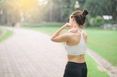 Güneydoğu Asyalı kadın sağlık ve sağlıklı yaşam tarzı kavramı ile parkta egzersiz yapıyor, rahatlıyor ve sabah güneşinin tadını çıkarıyor.