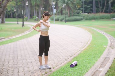 Güneydoğu Asyalı kadın rahatlama ve zindelik motivasyonu göstererek açık hava parkında egzersiz yaparak sağlık ve sağlıklı yaşam tarzı kavramı geliştiriyor.