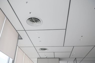 Temiz, modern bir ofis tavanı. Havalandırma delikleri, aydınlatma ve şebeke düzeni parlak ve düzenli bir atmosfer yaratıyor. Tasarım basit ve işlevseldir