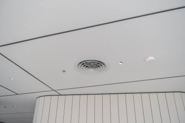 Temiz, modern bir ofis tavanı. Havalandırma delikleri, aydınlatma ve düzgün beyaz panellerle şebeke deseni parlak ve profesyonel atmosfer yaratıyor.