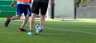 Yeşil çimlerin üzerinde hareket eden bir futbolcu oyun sırasında bacaklarına ve toplarına odaklanıyor, açık hava sporlarında hareket ve rekabet gösteriyor