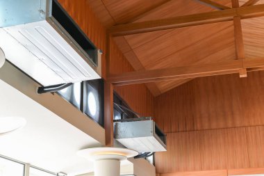 Ahşap kasalı tavana monte edilmiş modern Hvac kanal sisteminin yakın görüntüsü. Parlak iç uzayda ortaya çıkan kirişler mimari ayrıntıları ve havalandırma bileşenlerini gösteriyor.