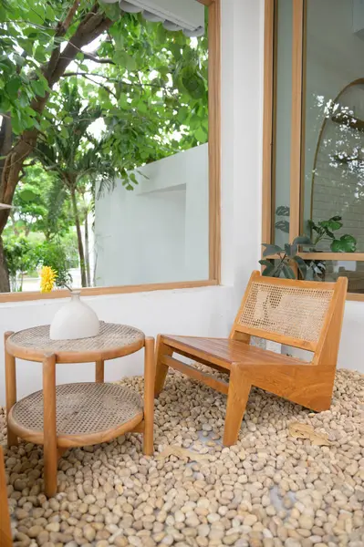 İçinde ahşap sandalye ve vazolarla çevrili yeşil ağaçların gölgesi altında gevşemek için mükemmel taşlarla çevrili yuvarlak bir masa olan rahat bir açık hava oturma alanı.