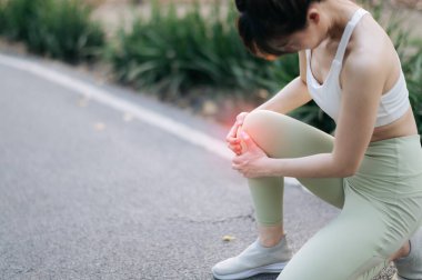 Güneydoğu Asya 'lı genç bir bayan sporcu parkta koşuyor. Egzersiz sırasında acı çekiyor ve sağlık konusunda endişe duyuyor. Antrenman sırasında diz ağrısı çeken Asyalı kadın..
