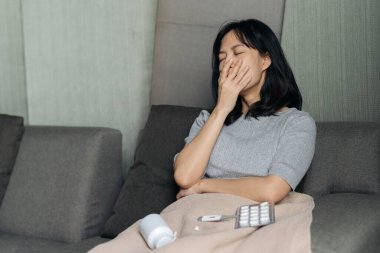 Mutsuz, sağlıksız, güneydoğu Asyalı bir kadın internette sağlık sigortası koruma planı arıyor. Bu sağlık sigortasının korunma garantisi için bir simgesi.