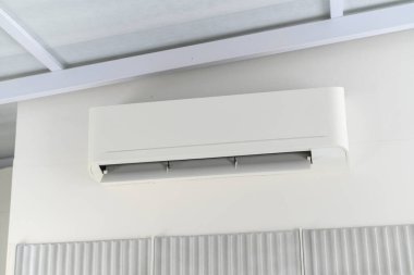Konforlu bir soğutma ve iklim kontrolü sunan modern beyaz klima ünitesi kapalı bir duvarda duruyor. Temel teknoloji sıcaktan kurtulmayı ve hoş bir ortam yaratmayı sağlar.