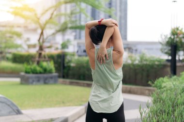 Asyalı bir kadın şehirli bir kadın esneme egzersizi yaparak fitness yogası yapıyor. Omuz ağrısı, kas gerginliği, iltihap ve tıbbi yaralanma riskini azaltır. Sağlık ve sağlık günbatımı riskini.