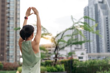 30 'ların fitness yoga antrenmanında Asyalı bir kadın. Gerinme egzersizi, tıbbi yaralanmaları, omuz ağrısı, kas iltihabı riskini azaltır. Şehir günbatımında sağlıklı yaşam tarzı sağlık hizmetleri