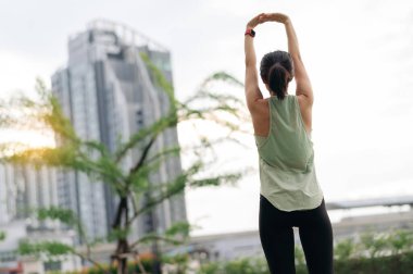 30 'ların fitness yoga antrenmanında Asyalı sakin bir kadın. Gerinme egzersizi, tıbbi yaralanmaları, omuz ağrısı, kas iltihabı riskini azaltır. Sağlık hizmetleri kentsel şehir günbatımı sağlıklı yaşam tarzı