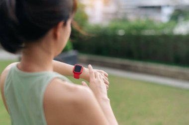 Odaklanmış Asyalı kadın 30 'lu yaşlarda nabzı kontrol ediyor. Şehir idmanından sonra akıllı bir nabız. Teknoloji kol saati kullanarak sağlıklı yaşam tarzını ve sağlık hizmetlerini destekleyen fitness egzersizi.