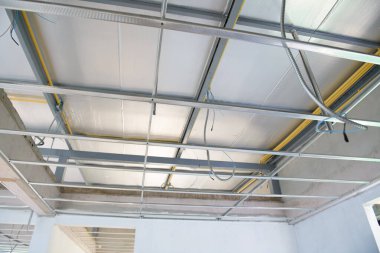 Yeni asılmış tavanın kurulumunu gösteren bir iç yenileme projesi. Alüminyum çerçeve, inşaatın umutlu ilerlemesi ışığında elektrik kablolarını tutuyor