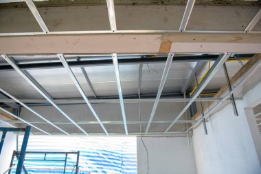 Odaklı bir iç yenileme alüminyum tavan iskeletinin açıkta kalan elektrik kablolarıyla kurulduğunu gösteriyor. karmaşık süreç ev geliştirme projesinin bir parçasıdır