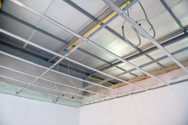 İç yenileme sırasında alüminyum tavan iskeletine odaklanmış bir bakış. Elektrik tesisatı kurulumu yeni modern ofis alanı için karmaşık ızgara sistemi gösteriyor