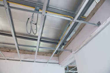 Yeni alüminyum tavan iskeleti içerisindeki elektrik kablolarını ev iyileştirme projesinin bir parçası olarak gösteren iç yenileme çalışmalarının ayrıntılı bir görünümü