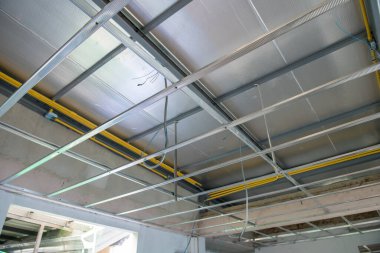 Tavan iskeleti kurulumunu gösteren iç dekorasyonun odaklanmış görüntüsü. Açığa çıkan elektrik kabloları, ev inşaatı sırasında yeni alüminyum panellerle birlikte çalışıyor