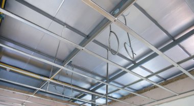 Bir iç yenileme projesi sırasında alüminyum tavan iskeleti ve elektrik kabloları kurulumunu gösteren bir ilerleme hissi endüstriyel bir atmosfer yaratıyor