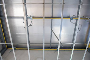 İç yenileme sırasında tavan inşaatına odaklanmış bir bakış. Metal çerçeve karmaşık elektrik kabloları kurulumu ile alüminyum yalıtımı destekliyor