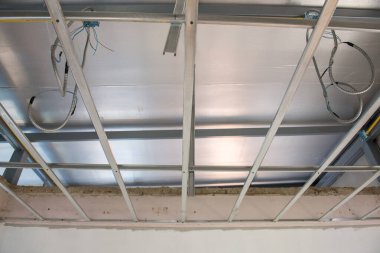Büyük bir iç yenileme sırasında dağınık elektrik kablolarına sahip alüminyum tavan iskeleti. Yeni bina için ızgara kurulum ve yalıtım malzemelerine odaklanmış görünüm