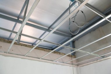 Bir iç yenileme projesi, yeni alüminyum tavan iskeleti içindeki elektrik kablolarının kurulumunda ilerleme kaydedildiğini gösteriyor. Bina yapımı ve tasarım çalışmalarına ayrıntılı bir bakış