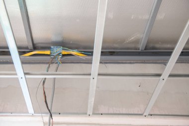Açıkta kalmış elektrik kablolarıyla alüminyum tavan iskeletine yakın çekim. askıya alınmış yapının ham kurulum ve yenileme sürecini gösteren bir iç görünüm