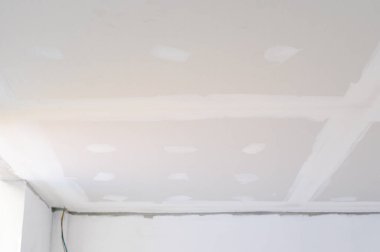 İç bina tadilatı alçıtaşı tavanının pürüzsüz kenarları olduğunu gösteriyor. Duvara yakın elektrik kabloları düz tavanlar yapıldığını gösteriyor.