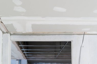 Alçıtaşı tavan kenarları pürüzsüz sıva ile devam eden iç yenileme elektrik kablosu çalışmalarını gösteriyor. İnşaat sürecinin ilerleyeceği binanın tavanlarını vurguluyor.