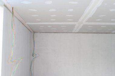 İç yenileme sırasında alçıtaşı tavanının pürüzsüz kenarları elektrik tellerini ve pürüzsüz alçılama tavanlarını gösteriyor.