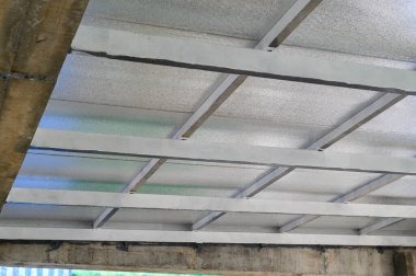 Gri metal levhalar, sağlam destek ve izolasyon içeren bir üst yapı oluşturur. Pu köpüğü gibi endüstriyel malzemeler tavanı kaplamak için güvenlik ve dayanıklılık hissi verir