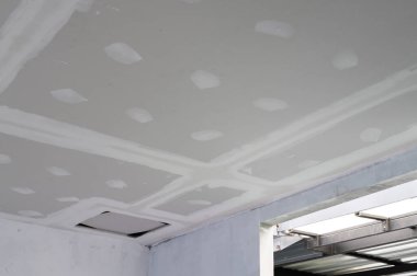 İç yenileme işlemi alçıtaşı tavan kenarlarını pürüzsüz bir şekilde inşa ediyor. Tavandaki sıvalar kusursuz bir iş çıkardığını gösteriyor. Elektrik kablosu bitirme yolunda görünür yansıtma çabası