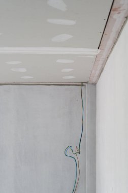 Pürüzsüz kenarlı alçıtaşı tavanı iç yenilemeden geçiyor. Elektrik teli duvarın yanında asılı. Bina tavanlarında pürüzsüz sıvama hazırlıkları görülebilir