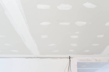 İç yenileme sırasında binanın içinde alçı taşı tavanı hazırlanıyor. Elektrik teli pürüzsüz kenarlar boyunca sıva çalışmalarının devam ettiğini gösteriyor.