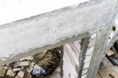 Ev tadilatı sırasında duvardaki beton kirişin yakın görüntüsü. İnşaat alanının dağınık yıkım aşaması gelişim kaosu gösteriyor