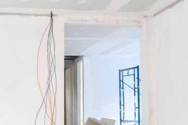 İç yenileme, alçıtaşı tavanı ve duvar kenarlarının elektrik tellerinin ilerlemesini gösterdiğini gösteriyor. Pürüzsüz alçı kaplama, müstakbel ev projeleri için bina tavanları.