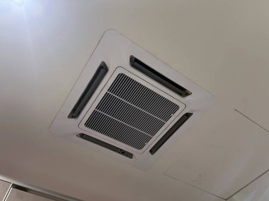 İç iklim kontrolü için beyaz tavana monte edilmiş modern kaset klima. Havalandırma sistemi rahat bir ev ya da ofis için serin ve temiz hava sağlıyor.