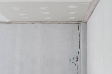 Alçıtaşı tavan, bina içinde iç yenileme için pürüzsüz kenarları var. Pürüzsüz sıva yüzeyde ilerlemeyi gösterir. Çalışmalarını gösteren bir elektrik teli asılmış.