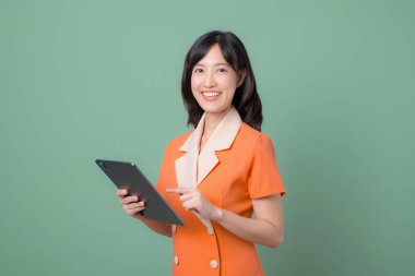 Güneydoğu Asyalı bir kadın gülümserken dijital tablette yeşil arka plana karşı internet kullanıyor, özgüven ve modern teknoloji yaşam tarzı gösteriyor