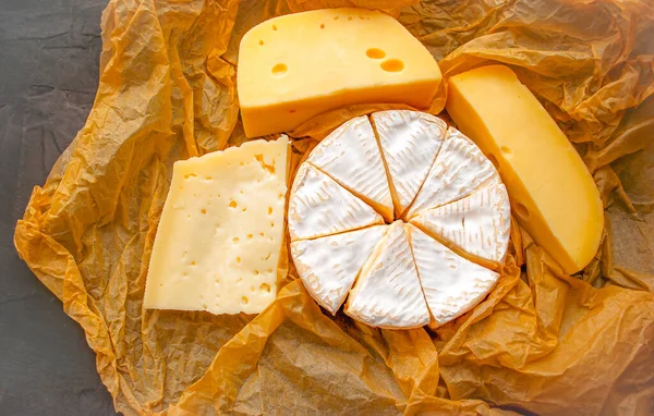 奶酪背景 羊皮纸上有不同类型的奶酪 奶酪店 — 图库照片