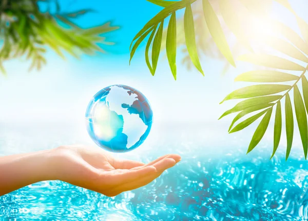 Water or World Oceans Day concept, International Day of the Tropics theme. Environmental conservation, protect clean planet Earth and ecology, sustainable lifestyle. Globe in hand on sea background.
