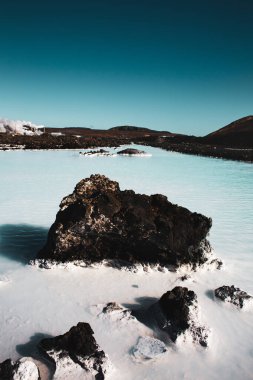 Mavi gölün mavi sularında siyah bir taş. Kaplıca güzellik salonu reklamı.