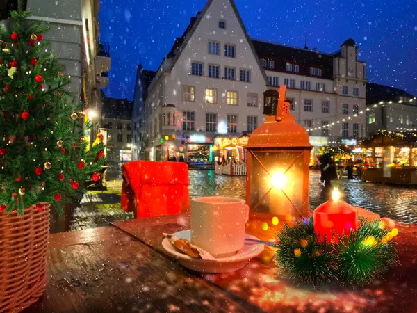 Christmas city evening street restaurant  table , cup tea ,decoration lantern and tree illuminated  , candle light in Tallinn old town hall square medieval city winter  holiday