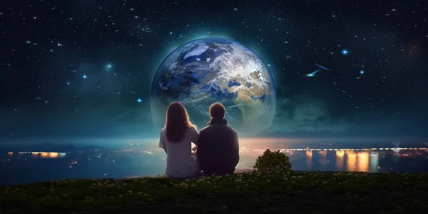 romantic young couple man and woman sit on rock at night sea watching starry sky and big moon on horizon mediterranean city blurred light reflection on water esoteric  surrealism