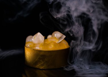 Dumanlı altın bir kutuda buz, renkli duman, mavi duman, gri duman, şerbetli buz, lezzetli buz. Koyu arkaplanda boşluk resmi