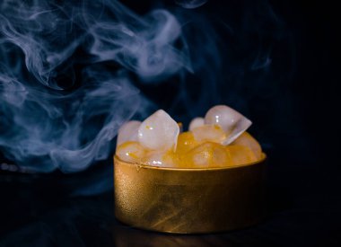 Dumanlı altın bir kutuda buz, renkli duman, mavi duman, gri duman, şerbetli buz, lezzetli buz. Koyu arkaplanda boşluk resmi