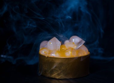 Dumanlı altın bir kutuda buz, renkli duman, mavi duman, gri duman, şerbetli buz, lezzetli buz. Koyu arkaplanda boşluk resmi